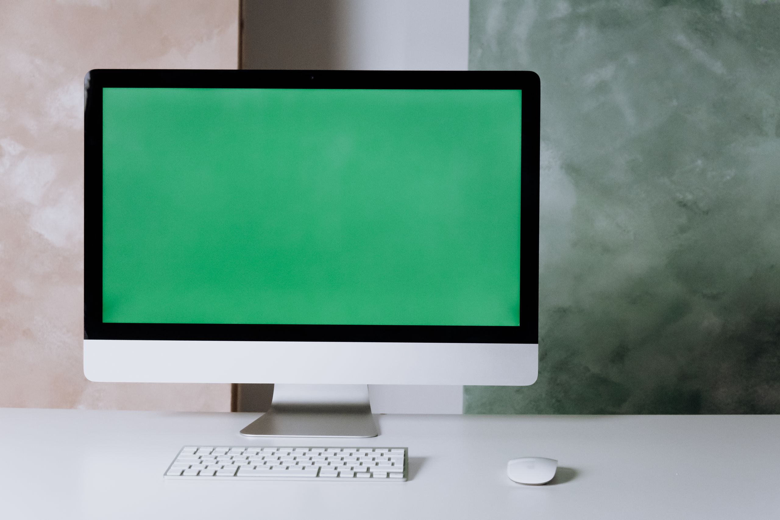 Clean and minimalist setup with a computer and green screen on a white desk.